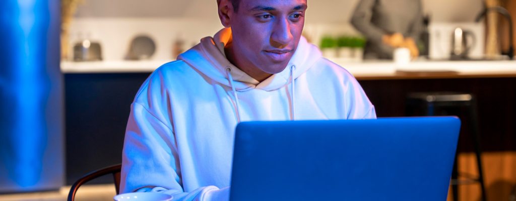 Imagem ilustrativa sobre luz azul e a saúde ocular mostrando um jovem exposto à luz artificial do computador.