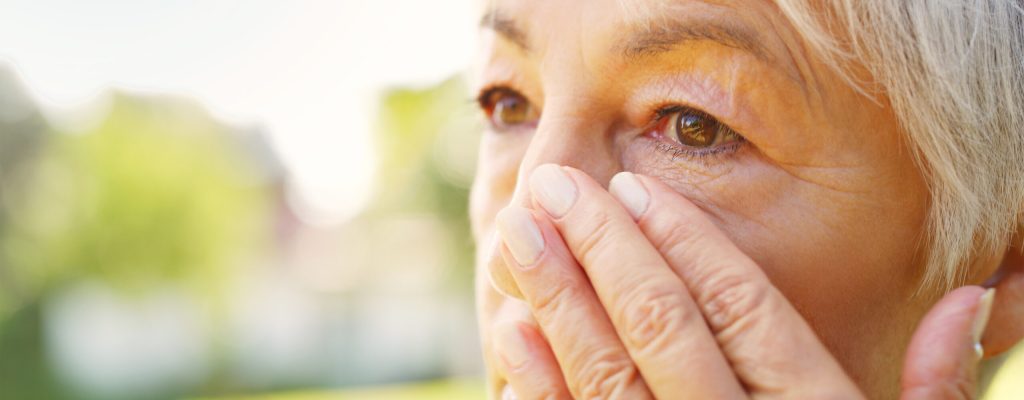 Idosa com a mão perto do olho. Imagem sobre o que é glaucoma e quais os sintomas.